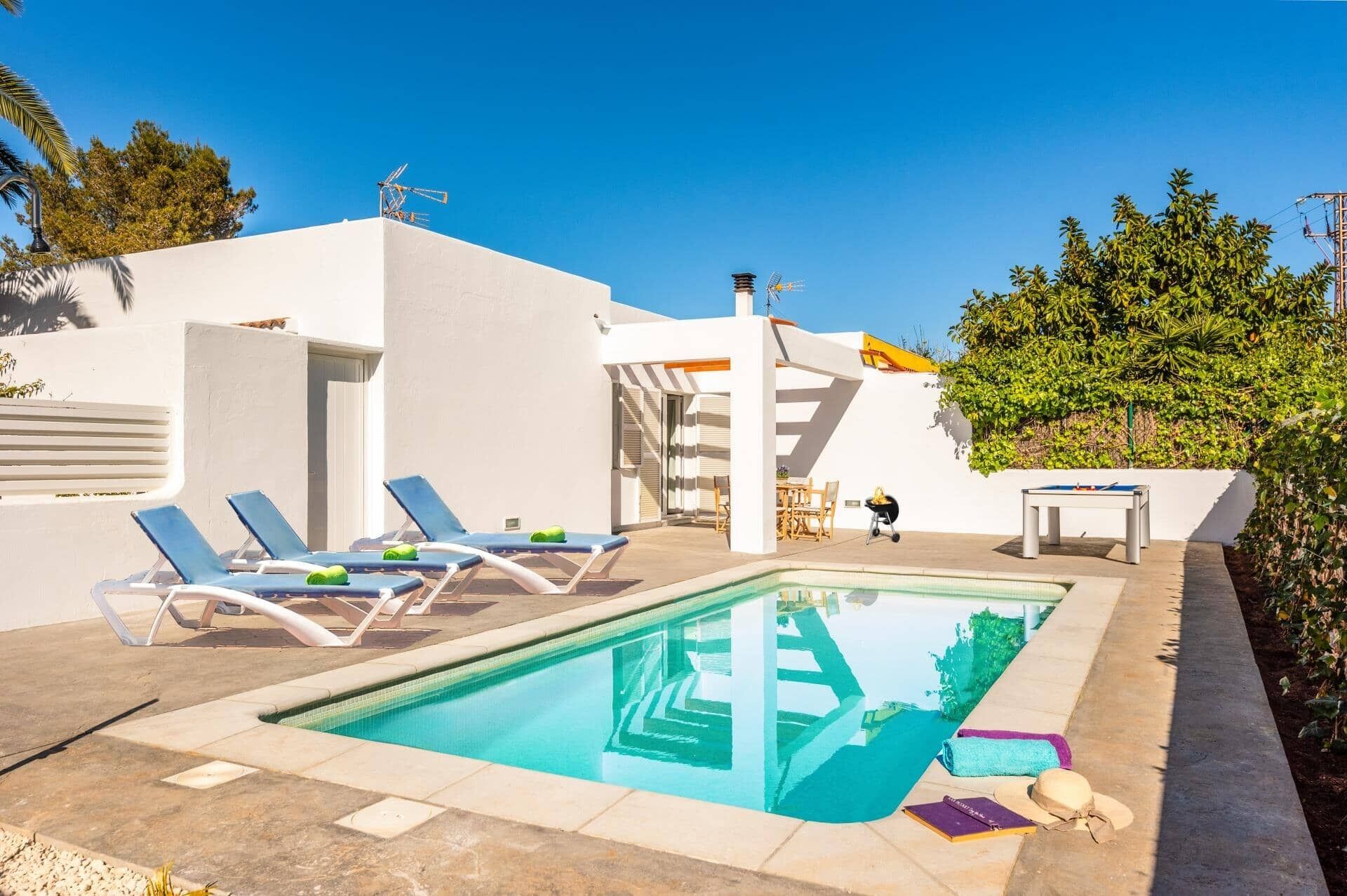 Un espace piscine aménagé avec des chaises longues, une table et une petite table sur laquelle est posé un jeu de société.