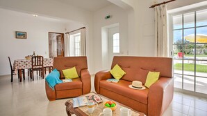A dining area with two leather sofas, a dining table with chairs, and a view of the outdoors. - Villa Casa Miguel by Villa Plus (Vale Rebelho)