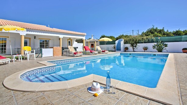 A swimming pool with lounge chairs and umbrellas, a tiled deck, and a building with a tiled roof. - Villa Casa Miguel by Villa Plus (Vale Rebelho)