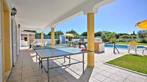An outdoor patio area with a ping pong table, chairs, and a pool. - Villa Casa Miguel by Villa Plus (Vale Rebelho)
