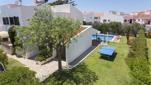 Una propiedad residencial con piscina, cancha de tenis y jardín con diversas plantas.