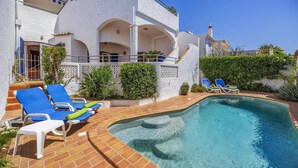 Uma área à beira da piscina com espreguiçadeiras e piscina.