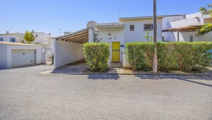 Um edifício residencial com porta amarela, garagem e entrada de automóveis em cascalho.