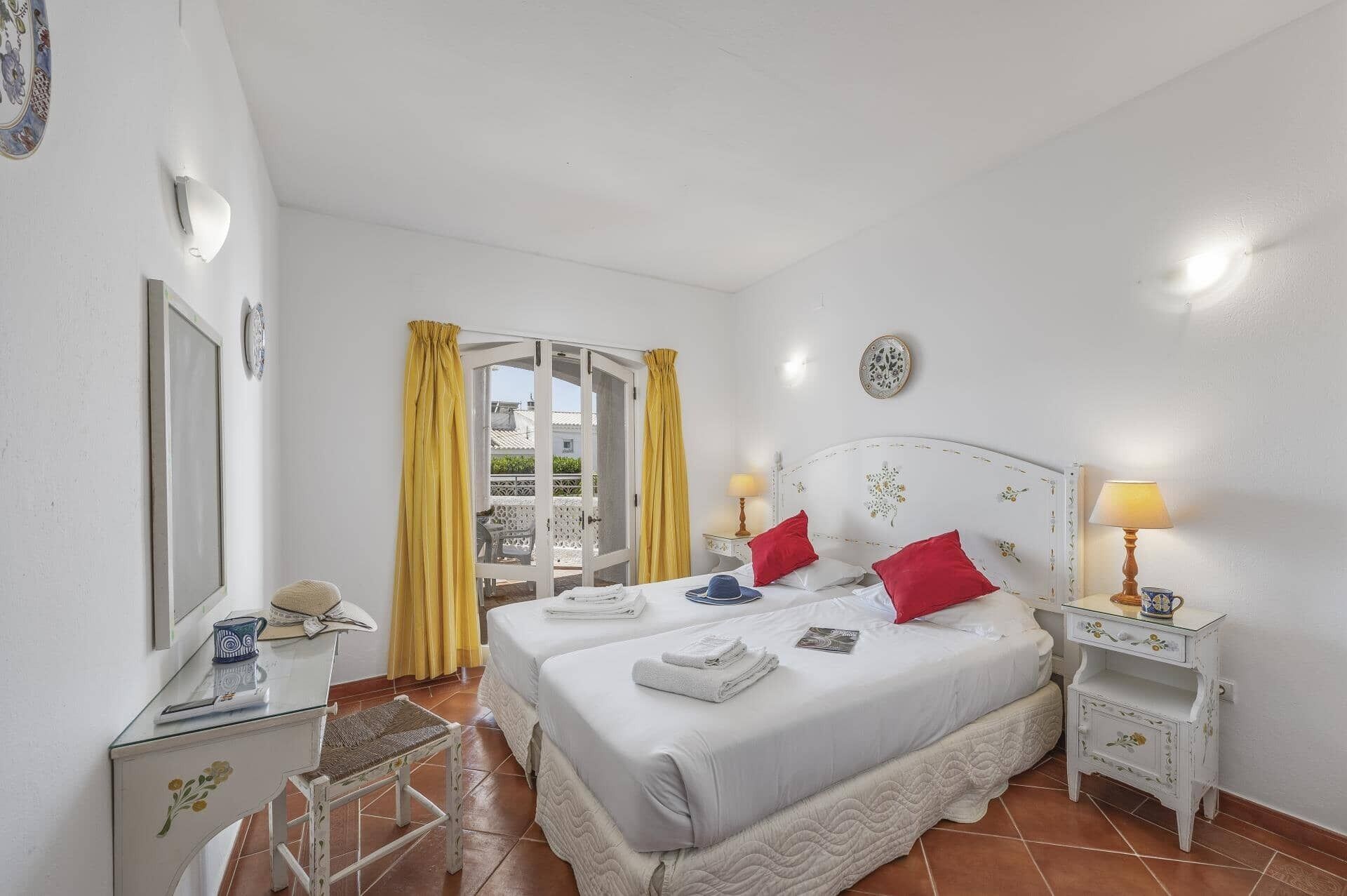 A hotel room with a bed, two bedside tables, a mirror, and a window with curtains.