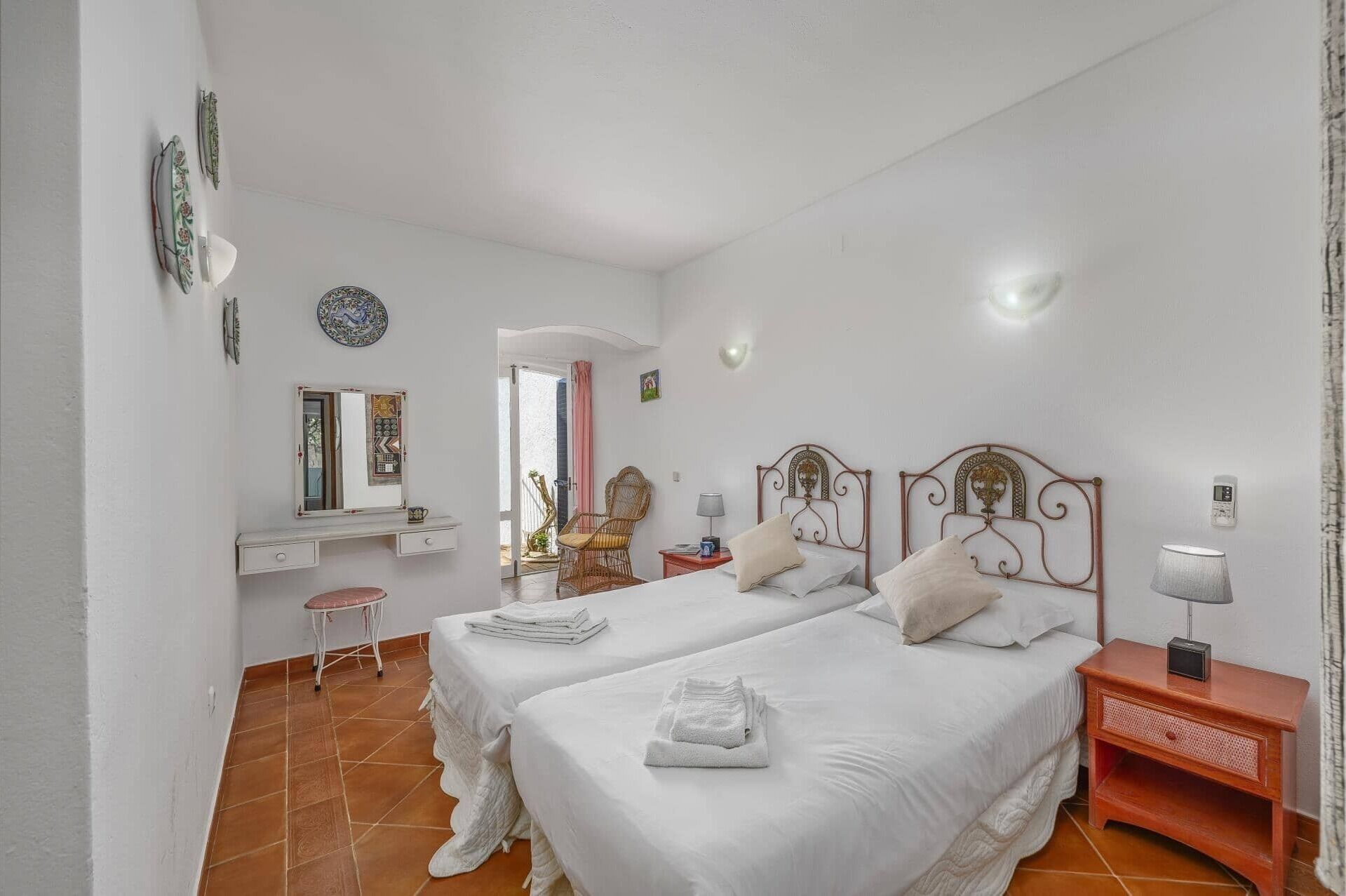 A bedroom with two beds, a desk, a chair, and a small table.
