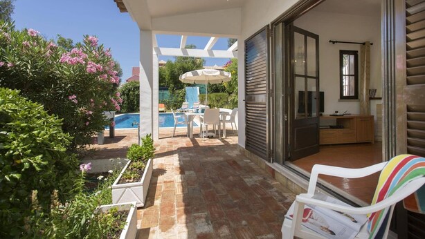Eine überdachte Terrasse mit Pool, Sitzgelegenheit im Freien und einer Glastür, die zu einem Raum führt.