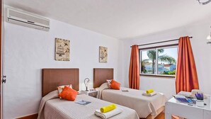 Ein Hotelzimmer mit zwei Betten, einem Schreibtisch und einem Fenster mit Vorhängen.