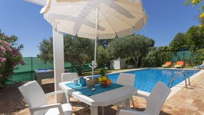 Ein Poolbereich mit Tisch, Stühlen und Sonnenschirm.