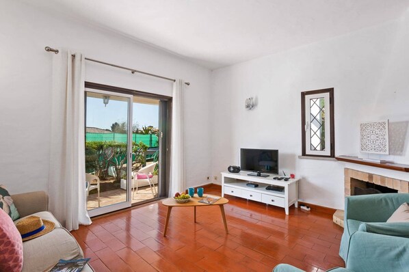Una sala de estar con televisor, chimenea y puerta corrediza al patio.