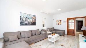A living room with two grey sofas, a white coffee table, and a cityscape painting on the wall. - Villa Calma by Villa Plus (Puerto del Carmen)