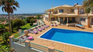 A two-story house with a swimming pool, lounge chairs, and a view of the landscape. - Villa Nenufa by Villa Plus (Albufeira)