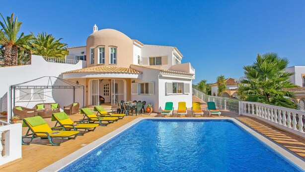 A poolside area with a swimming pool, lounge chairs, and a building with a white facade and a dome-shaped structure. - Villa Ninho da Aguia by Villa Plus (Albufeira)