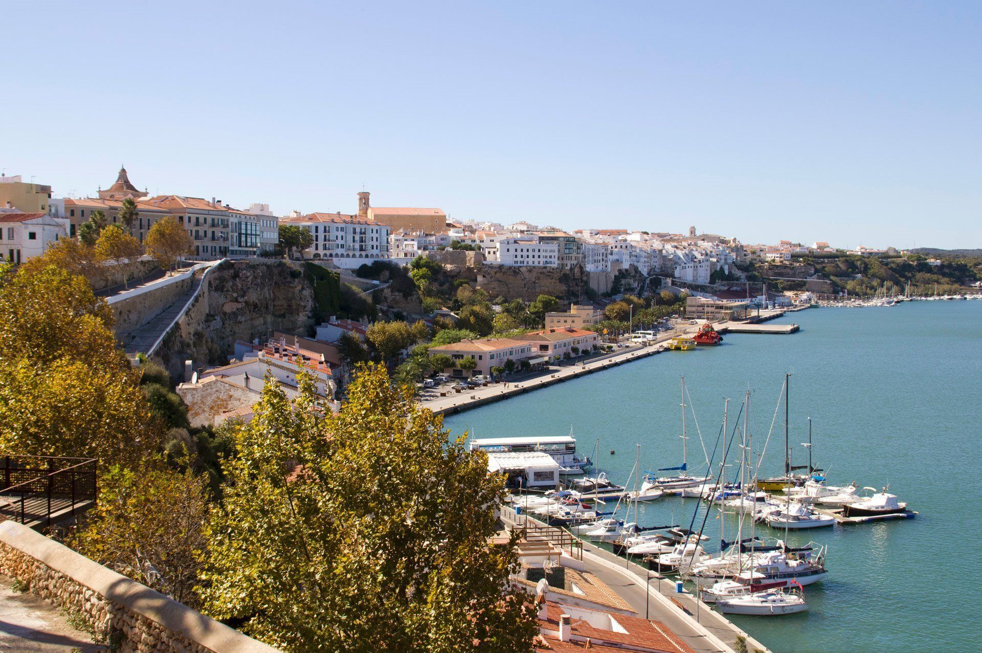 A coastal town with historic buildings, a marina with boats, and a prominent cliff overlooking the sea.