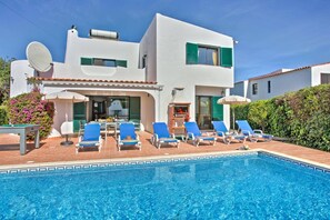 A modern two-story house with a swimming pool, outdoor seating, and a barbecue area.