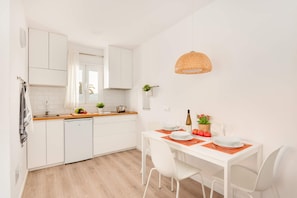 A modern kitchen with white cabinets, a wooden countertop, and a dining area with a white table and chairs.