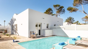 Un bâtiment moderne de couleur blanche, doté d’une piscine, d’un espace extérieur aménagé et d’un mur en pierre.