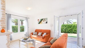 A bright living room with a sofa, a coffee table, and a painting on the wall. - Villa Carianne by Villa Plus (Son Carrió)