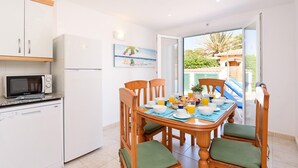 A kitchen with a dining area, a refrigerator, a microwave, and a table set for breakfast. - Villa Carianne by Villa Plus (Son Carrió)