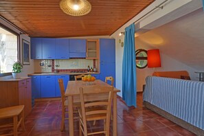 Cozy living space with a kitchen area, dining table, and sofa, perfect for relaxing and enjoying meals.