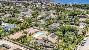 Une vue aérienne d’un quartier résidentiel avec des maisons, une piscine et une vue sur la mer.