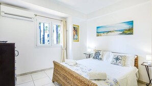 Une chambre à coucher avec un lit, une fenêtre, un tableau et une table de chevet.