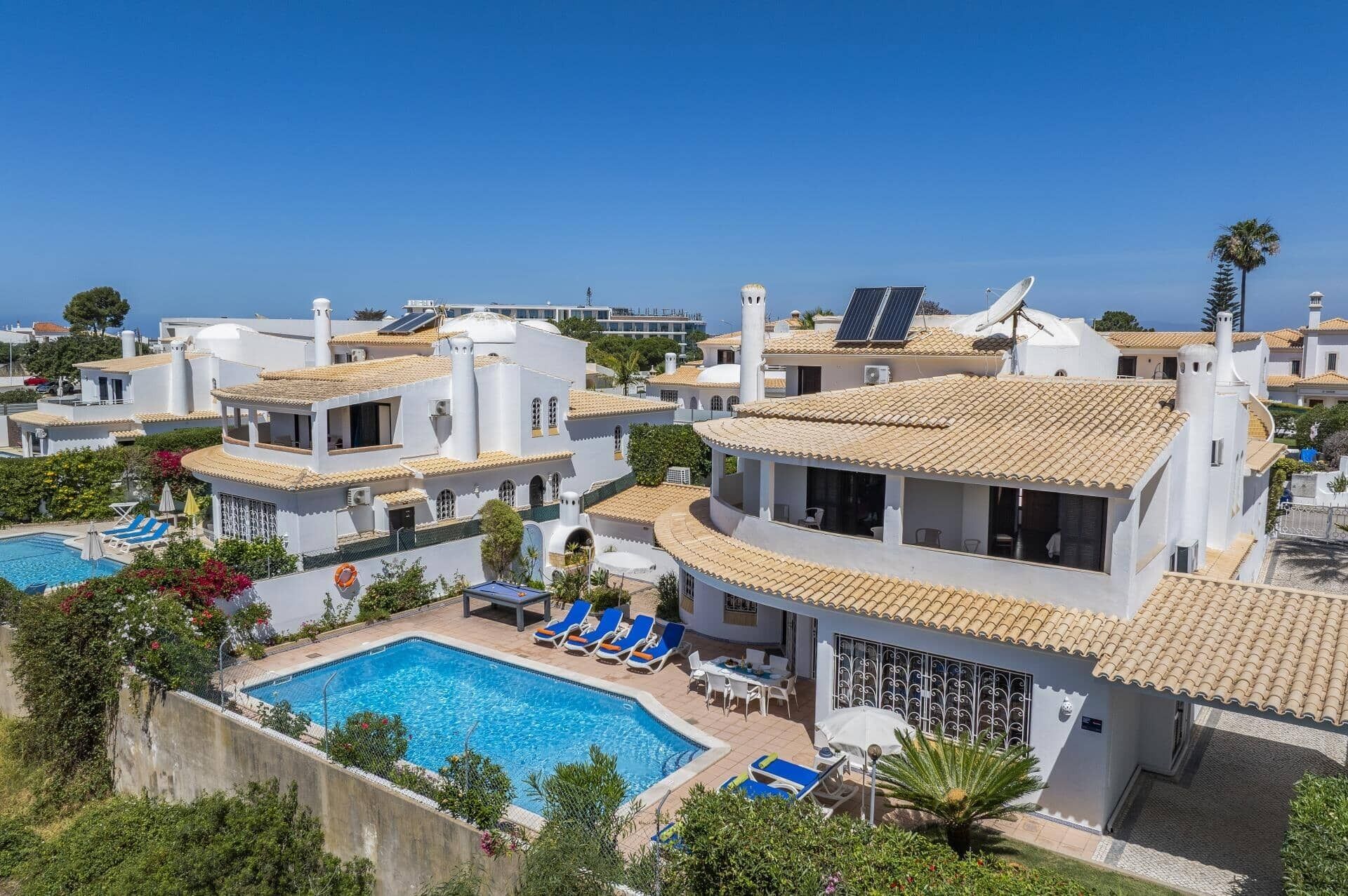 A resort with multiple buildings, a swimming pool, and solar panels.