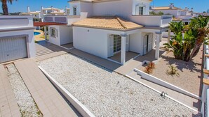 Una villa moderna con techo de tejas, paredes blancas y un porche cubierto.
