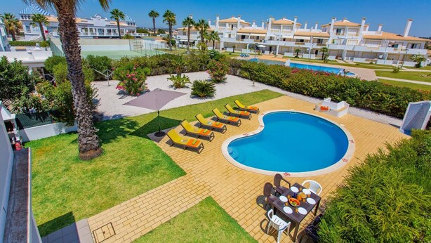 Un resort con piscina, sillones de descanso y zona de comedor.