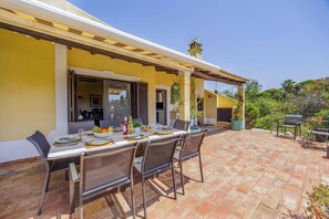 An outdoor patio with a dining table set for four, surrounded by chairs. - Villa Horta by Villa Plus (Lagoa)
