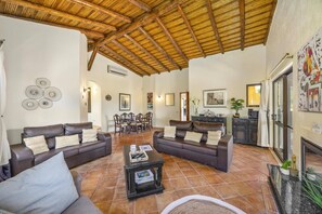 A spacious living area with leather sofas, a coffee table, and a dining area with chairs. - Villa Horta by Villa Plus (Lagoa)