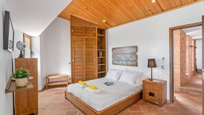 Une chambre avec un lit en bois, une petite table de chevet, une lampe de chevet, une armoire en bois, un globe terrestre et une carte accrochée au mur.