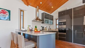 Une cuisine moderne avec un îlot central, des chaises en bois et une grande fenêtre.