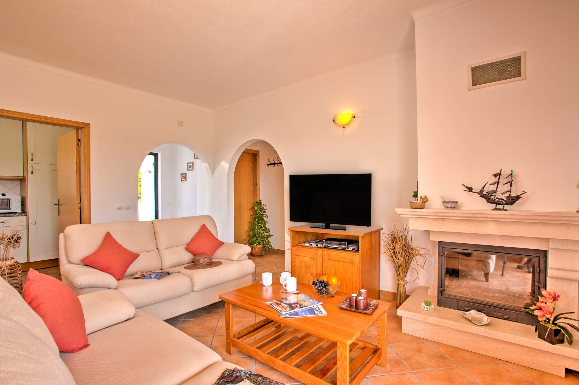 A living room with a sofa, coffee table, flat-screen TV, fireplace, and a dining area.