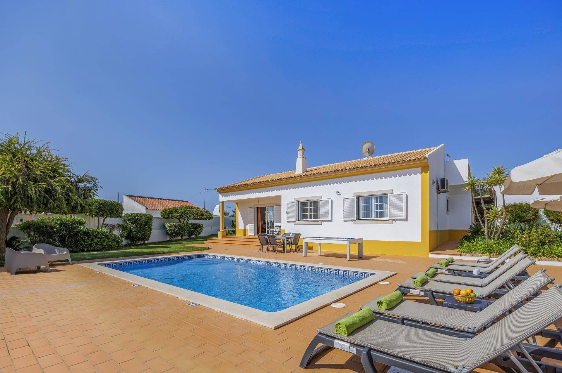 A two-story house with a swimming pool, outdoor seating, and a garden.