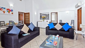 Ein modernes Wohnzimmer mit zwei dunklen Sofas, einem Glastisch und einem Wandbild mit einer Weltkarte.