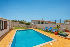A swimming pool with a tiled deck, surrounded by a fence, and a few lounge chairs. - Villa Neptuno Sol by Villa Plus (Albufeira)