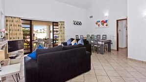 Ein Wohnzimmer mit einer Couch, einem Fernseher und einem Essbereich mit Stühlen und einem Tisch.