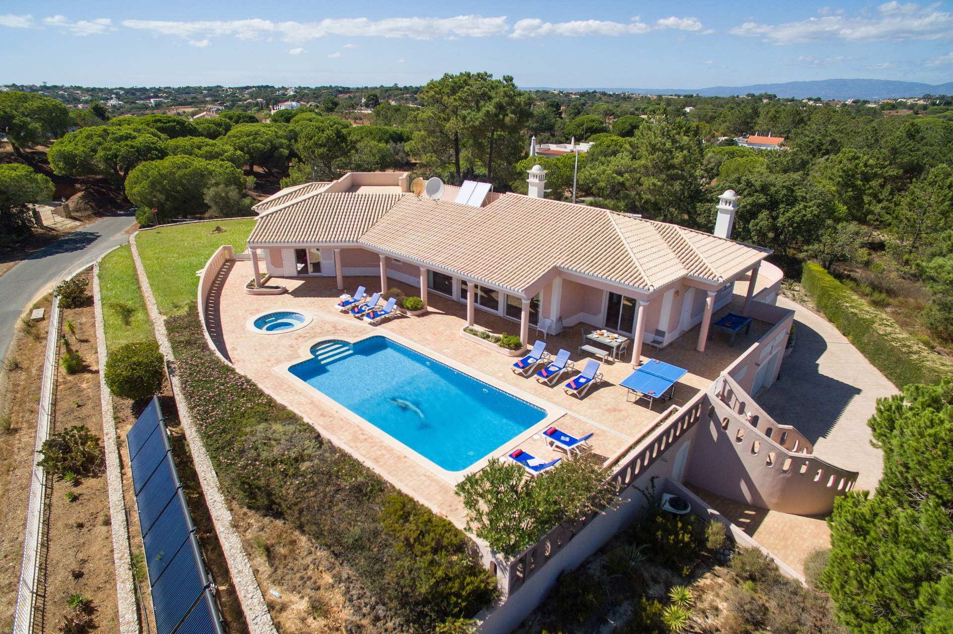 Una amplia villa con piscina, tumbonas y un patio cubierto.