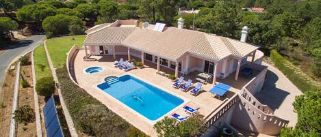 Una amplia villa con piscina, tumbonas y un patio cubierto.