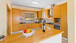 Eine moderne Küche mit Holzausstattung, Backofen, Mikrowelle und einem Fenster mit Blick auf einen Garten.