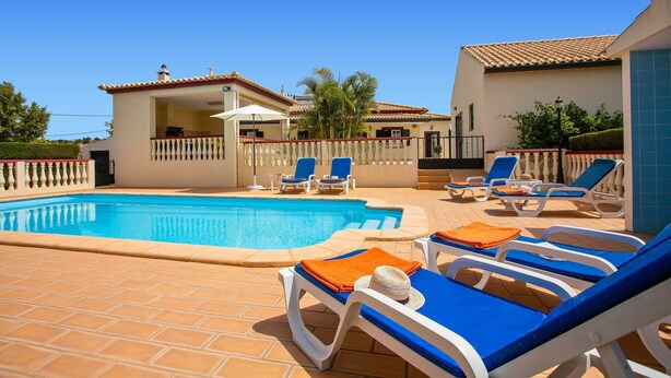 A swimming pool with lounge chairs and a covered patio area. - Villa Arvela by Villa Plus (Vale Rebelho)