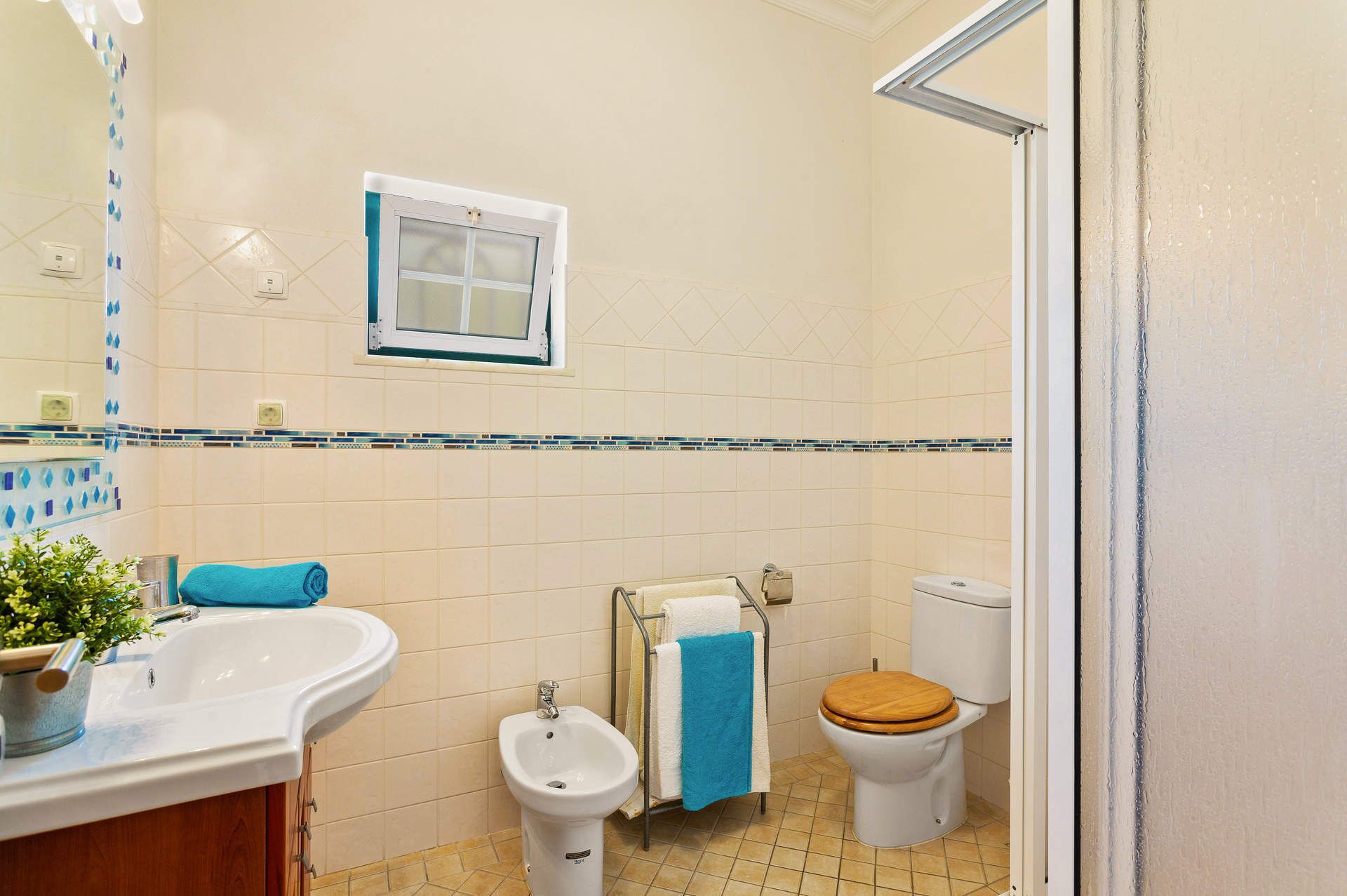 Een badkamer met een wastafel, bidet, toilet en een raam.