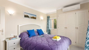 A bedroom with a bed, a bedside table, a wardrobe, and an air conditioning unit. - Villa Casa do Mel by Villa Plus (Loule)