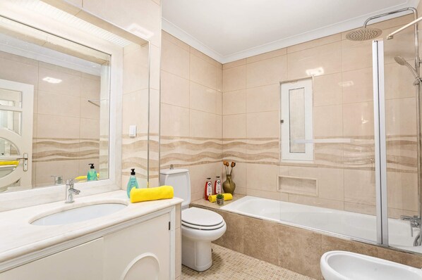 A modern bathroom with a bathtub, shower, and toilet.