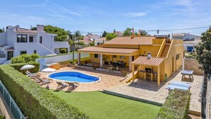 Een woonhuis met een zwembad, terras en overdekte patio.
