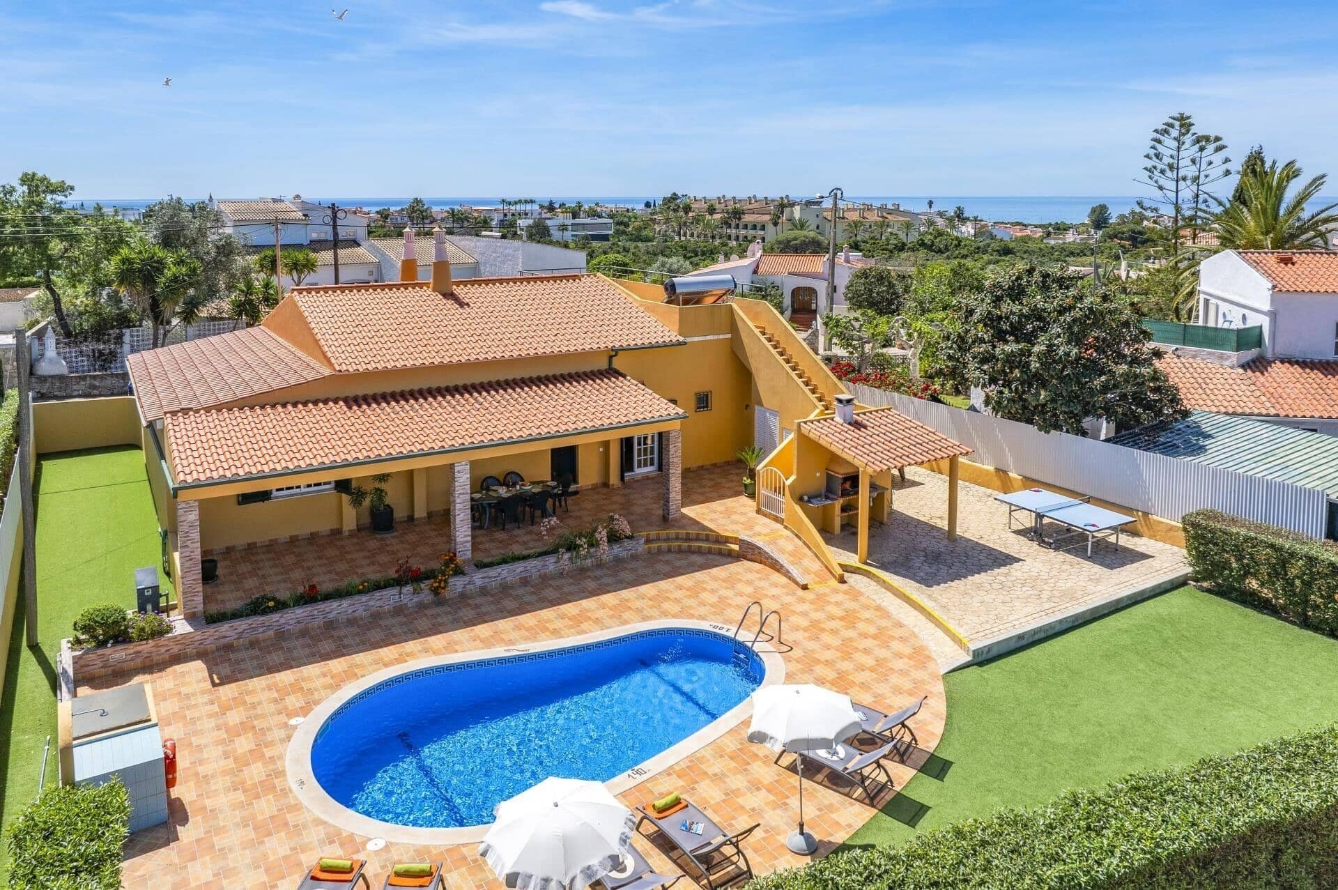 Una proprietà residenziale con piscina, area salotto esterna e vista sul mare.