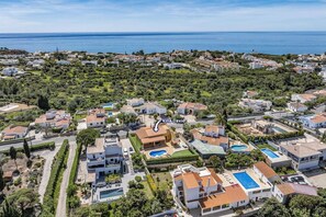 An aerial view of a coastal residential area with houses, a swimming pool, and a villa named Villa David. - Villa David by Villa Plus (Carvoeiro)