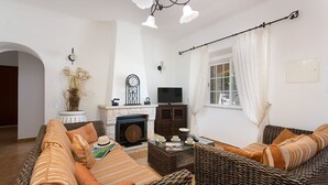 Een woonkamer met een open haard, bank en rieten meubels.