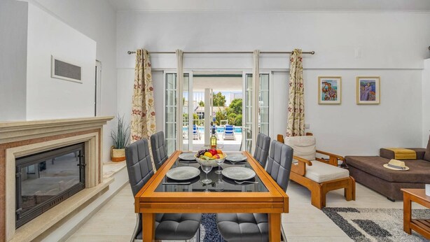 Una sala de estar moderna con comedor, chimenea y vista a una piscina.