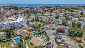 Vista aérea de una zona residencial costera con casas, piscina y una vista despejada del mar.